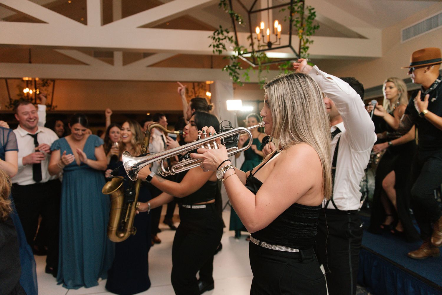 Live band performing at an indoor wedding reception with musicians playing instruments on stage.