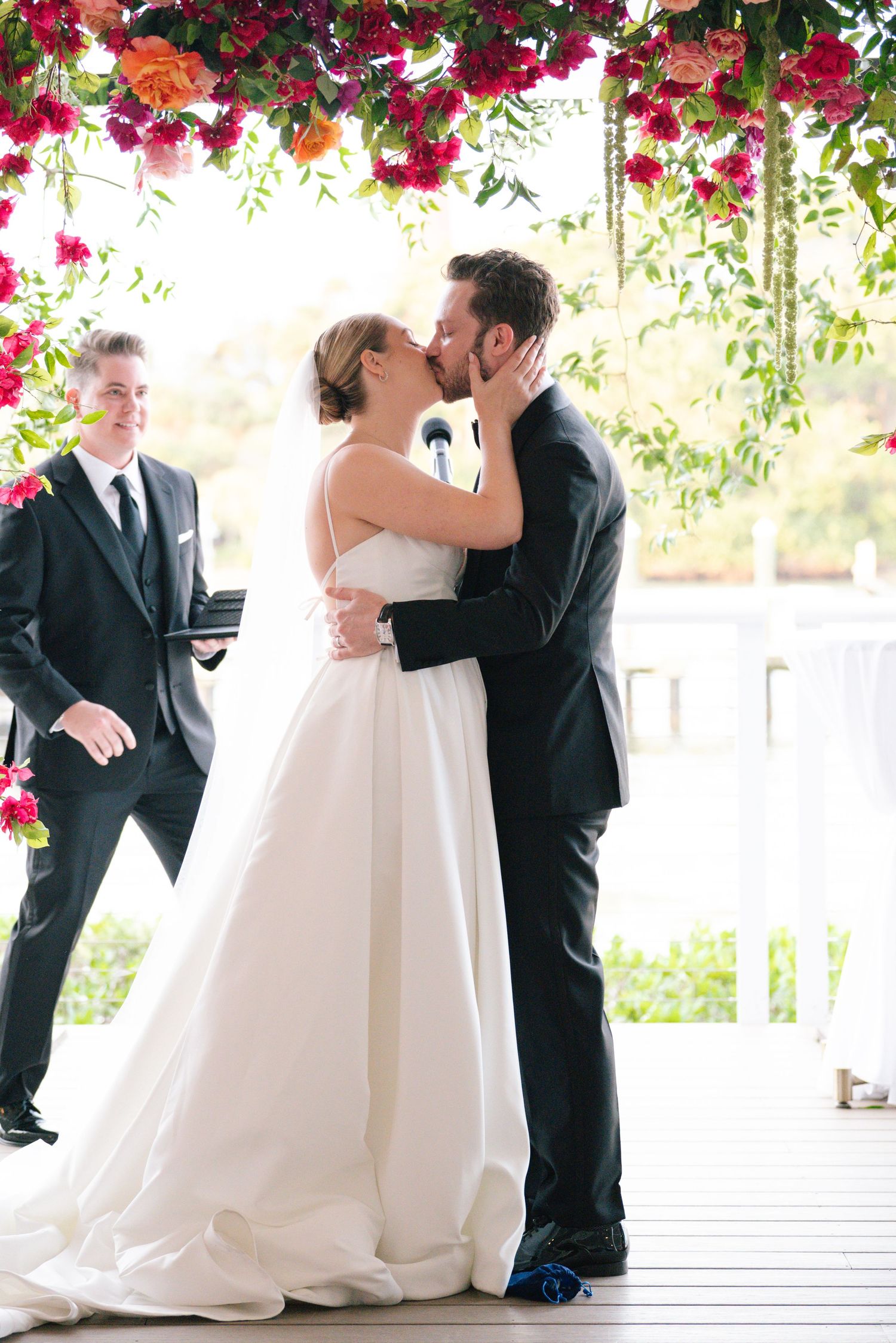A wedding ceremony moment under an archway decorated with vibrant pink bougainvillea flowers.
