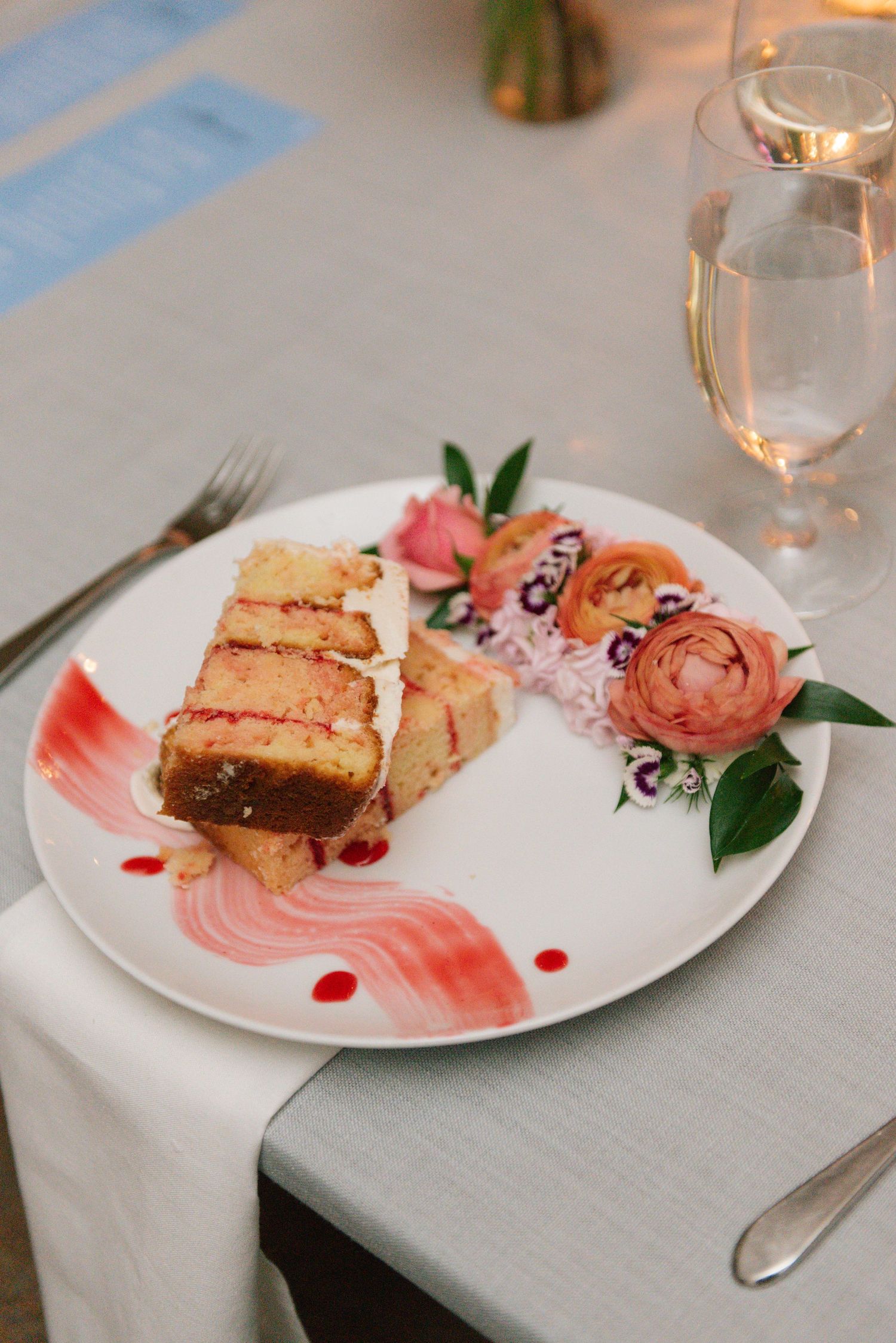 Plated wedding dessert with pink garnish and floral decoration.