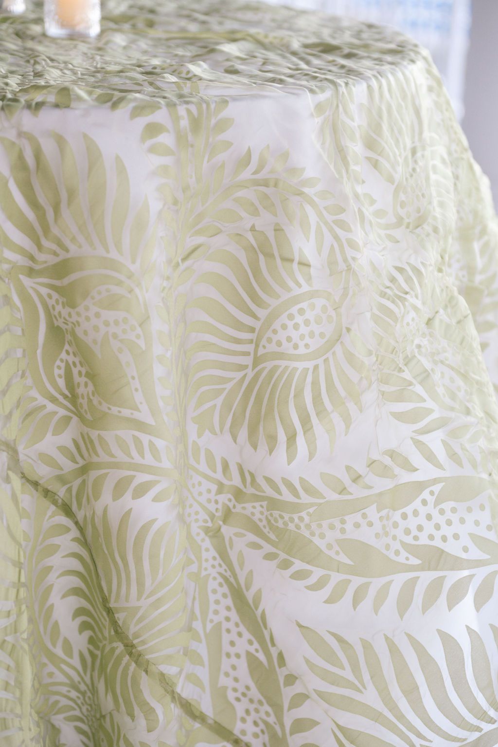Close-up of elegant cream tablecloth with embossed leaf pattern design.