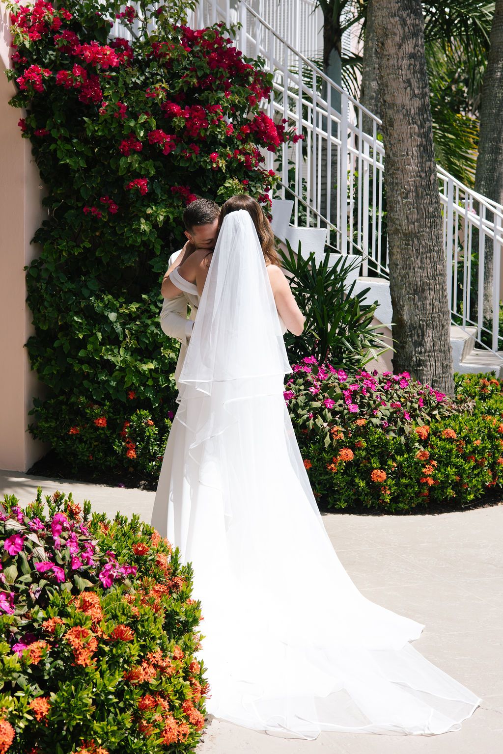 White wedding dress train spreads beautifully against vibrant pink and orange flowers.