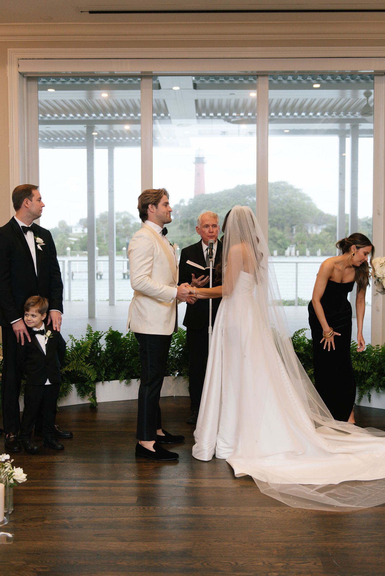 Wedding ceremony moments captured in a bright venue with large windows and hardwood floors.