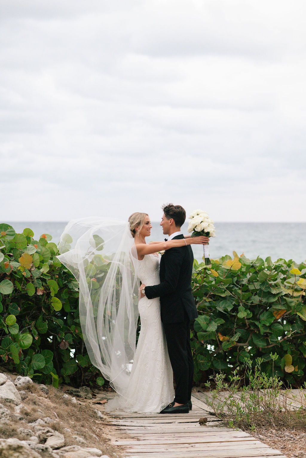 Romantic seaside wedding portraits with coastal vegetation.