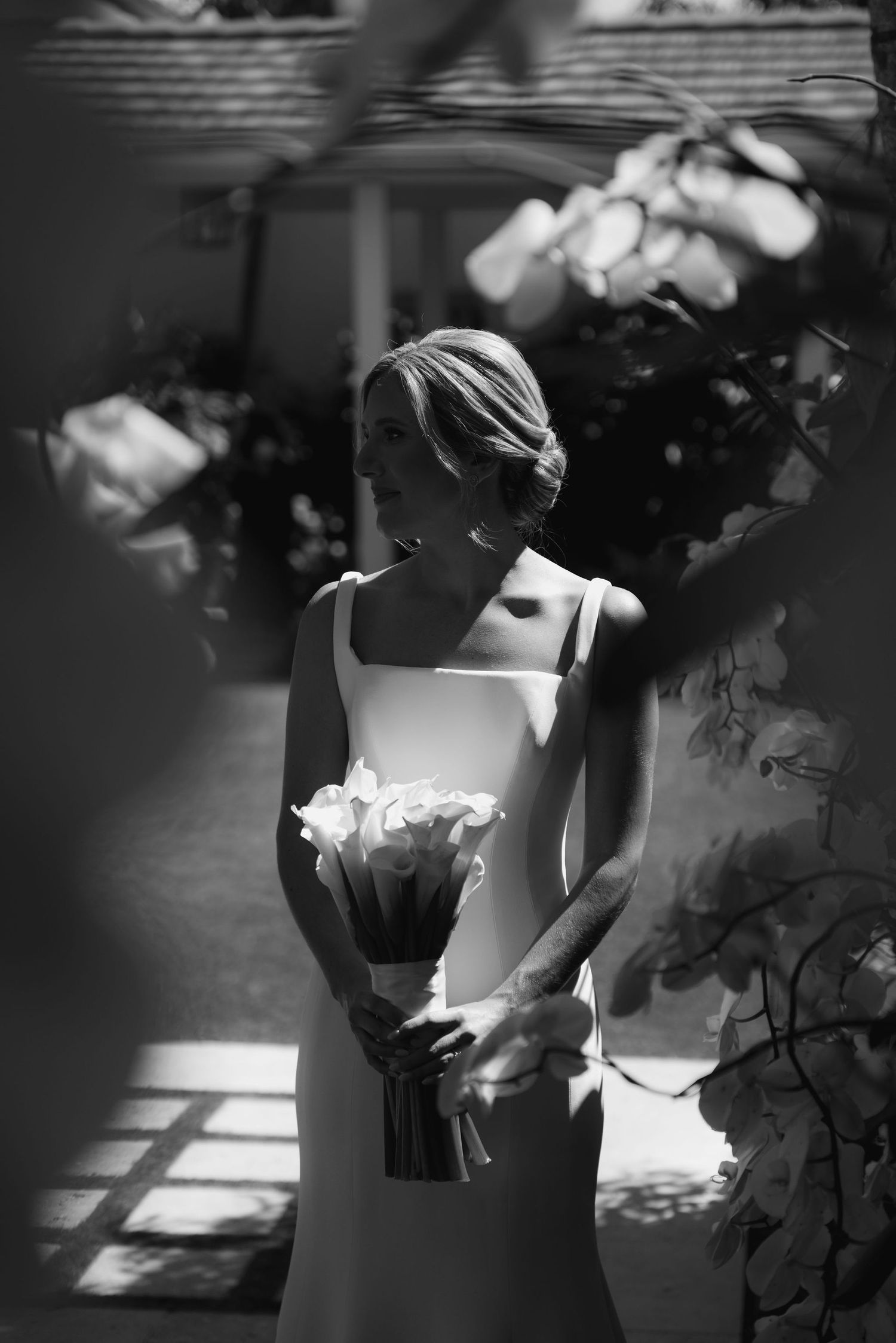 Artistic black and white bridal portrait with dramatic shadows and calla lily bouquet.