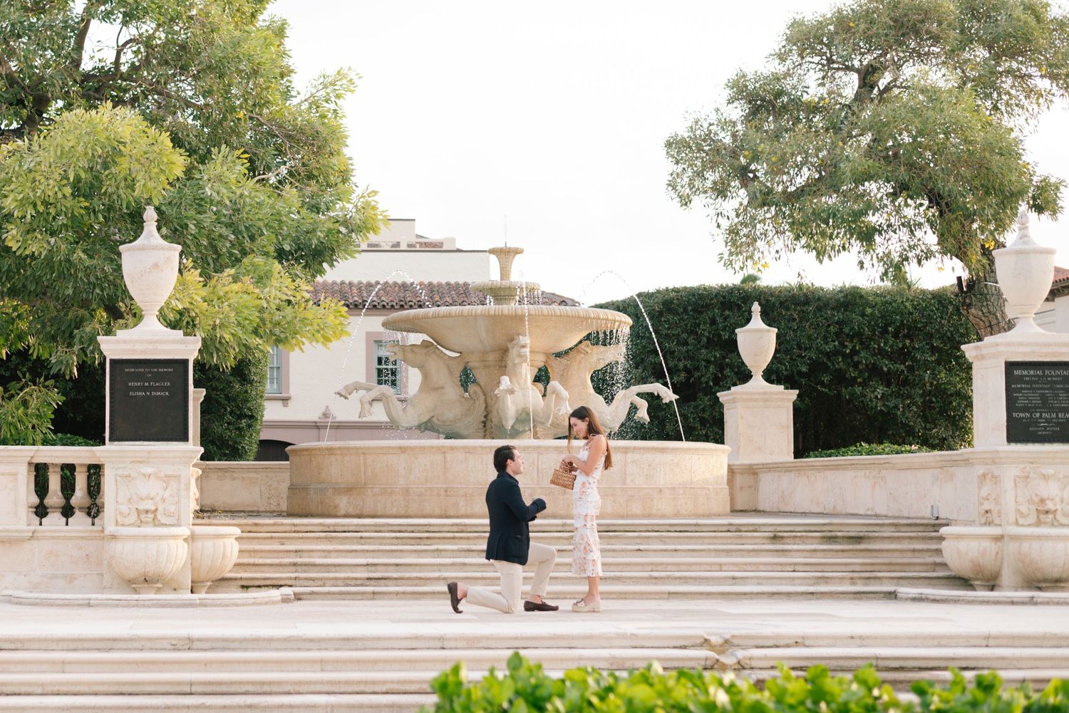 Two people dance together on elegant stone steps with decorative urns and a Mediterranean style villa in the background.