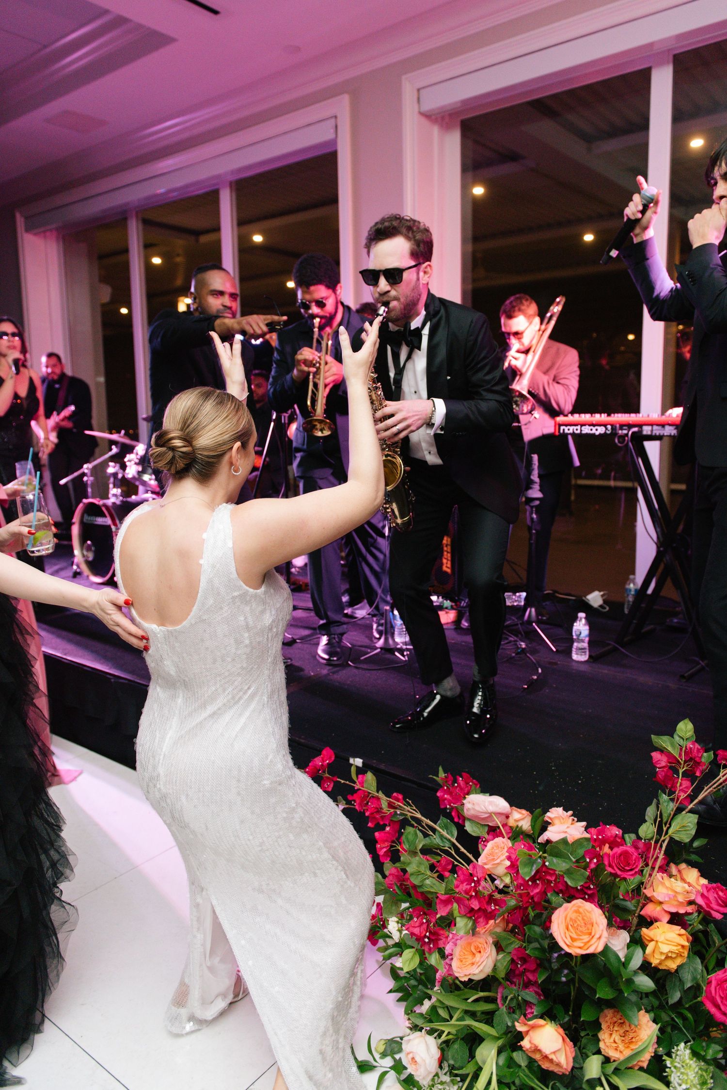 Live band performing at wedding reception with colorful floral arrangements in foreground.