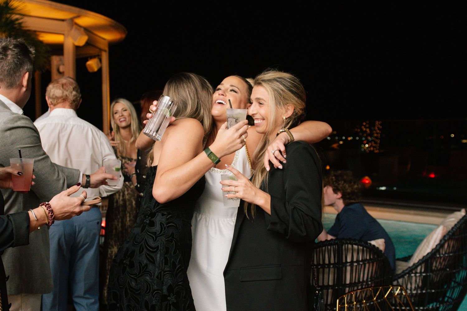 Wedding guests laugh and celebrate together at a lively reception party with cocktails and dancing.