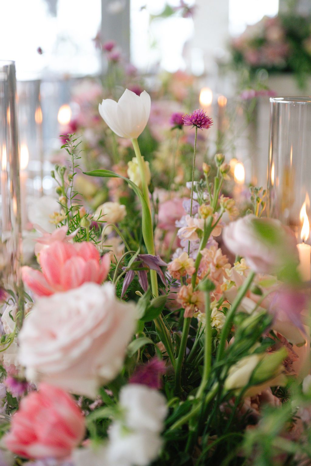 Romantic garden-style floral centerpiece with pink and white blooms in soft natural light.