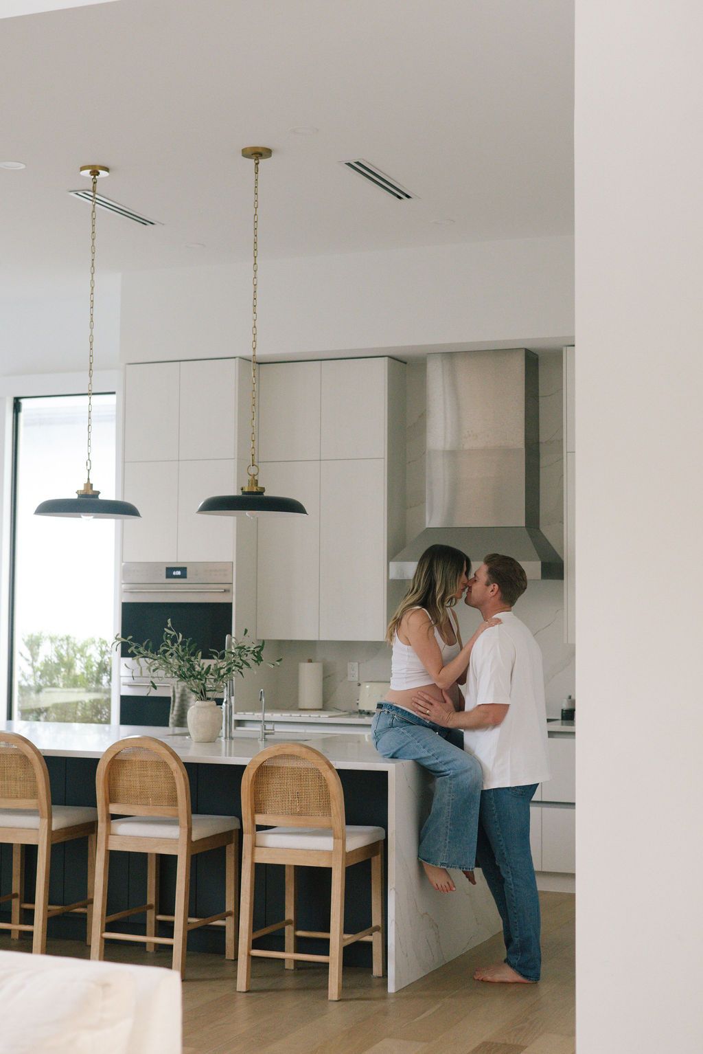Couple leaning against kitchen counter in white modern home interior.