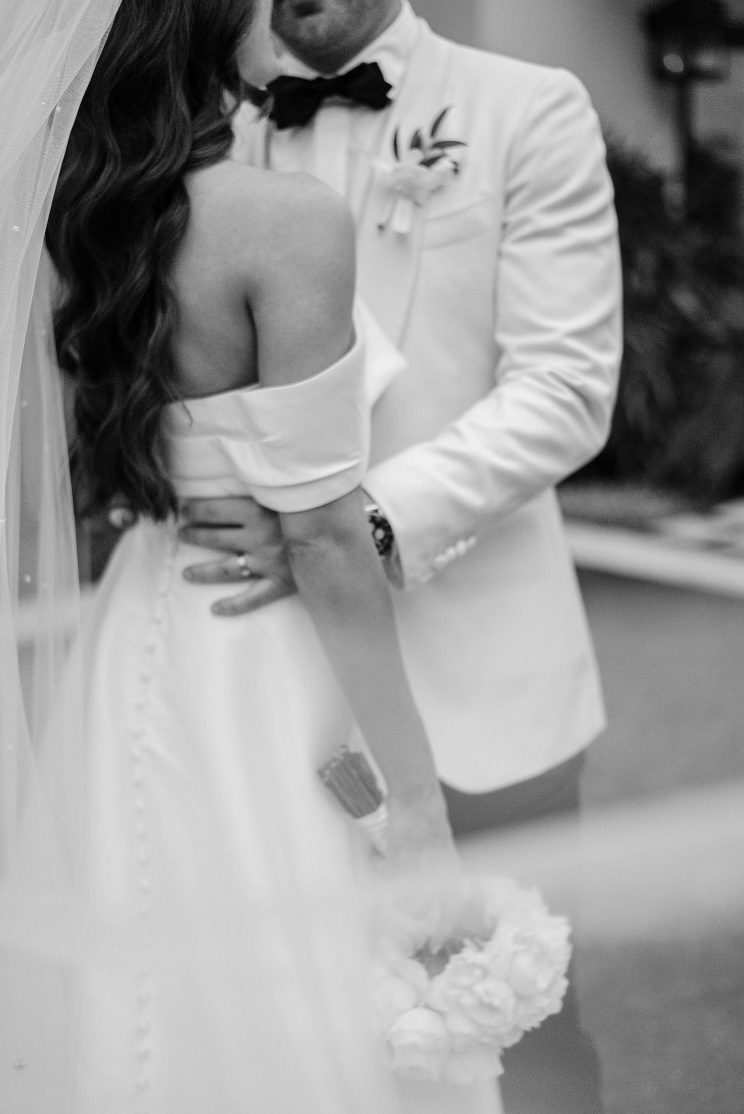 Romantic black and white wedding portrait showing bride and groom in intimate embrace.