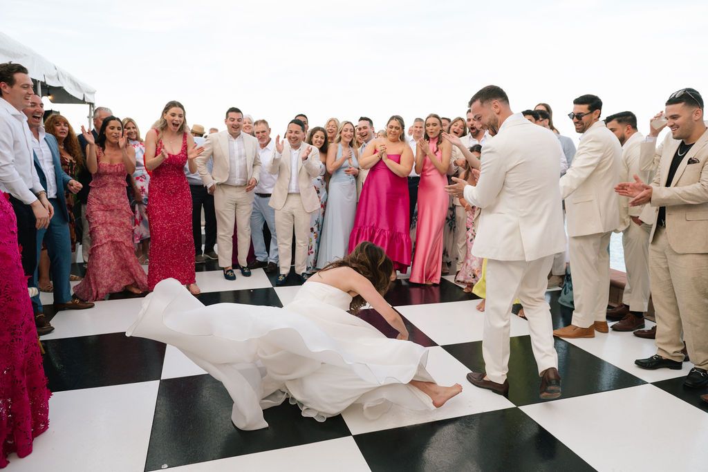 Wedding guests dancing and celebrating on a black and white checkered dance floor.