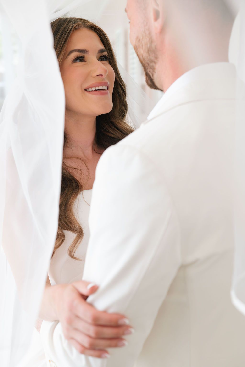 Romantic soft-focus wedding moment in white against a light background.