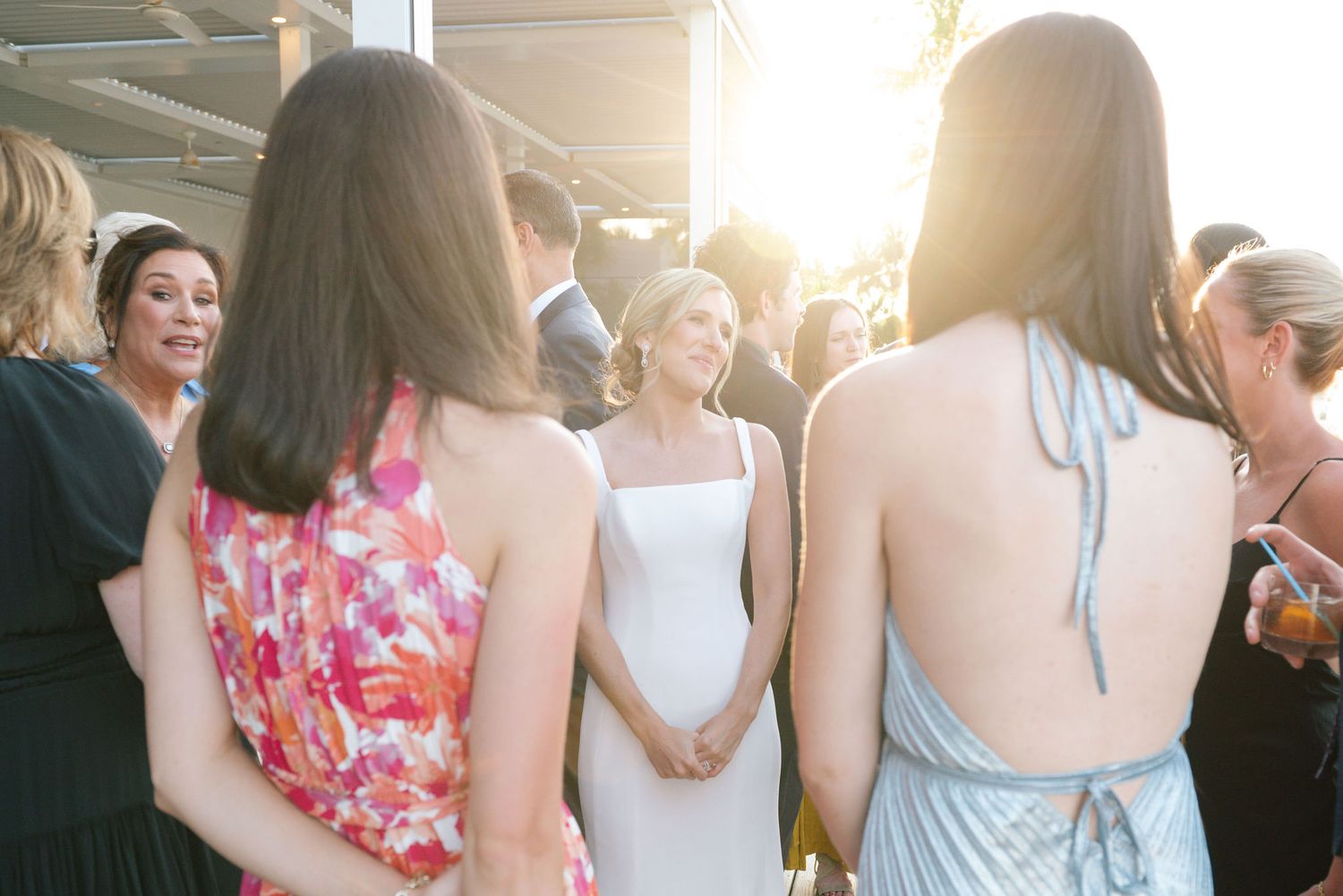 Wedding guests mingling outdoors during a sunset reception.