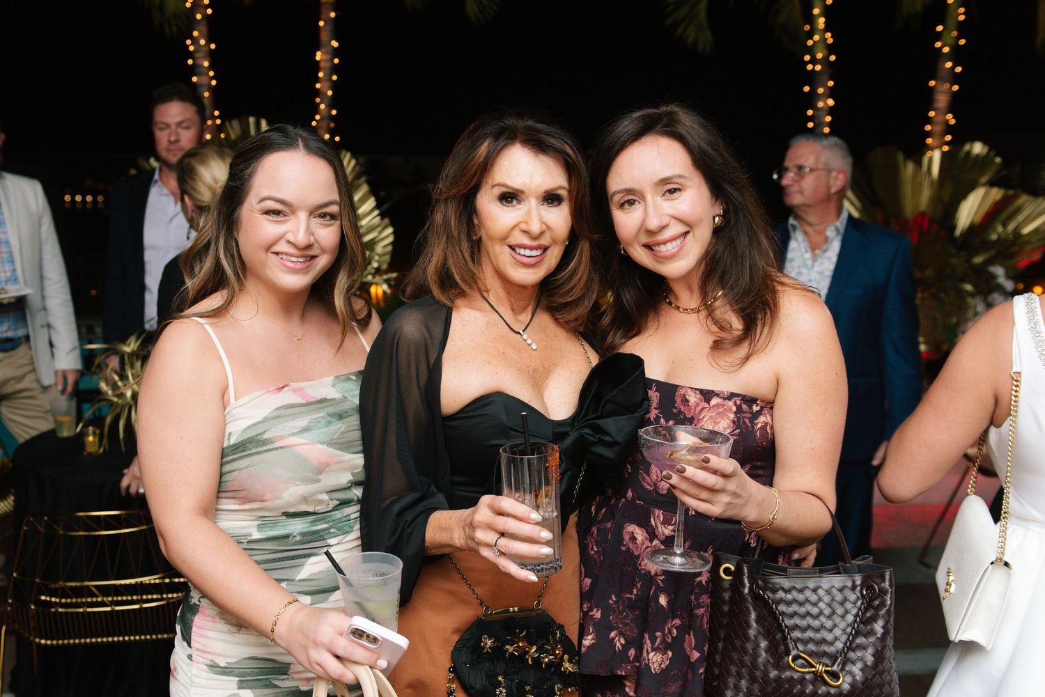 Group of party guests socializing at an evening event with festive lighting.