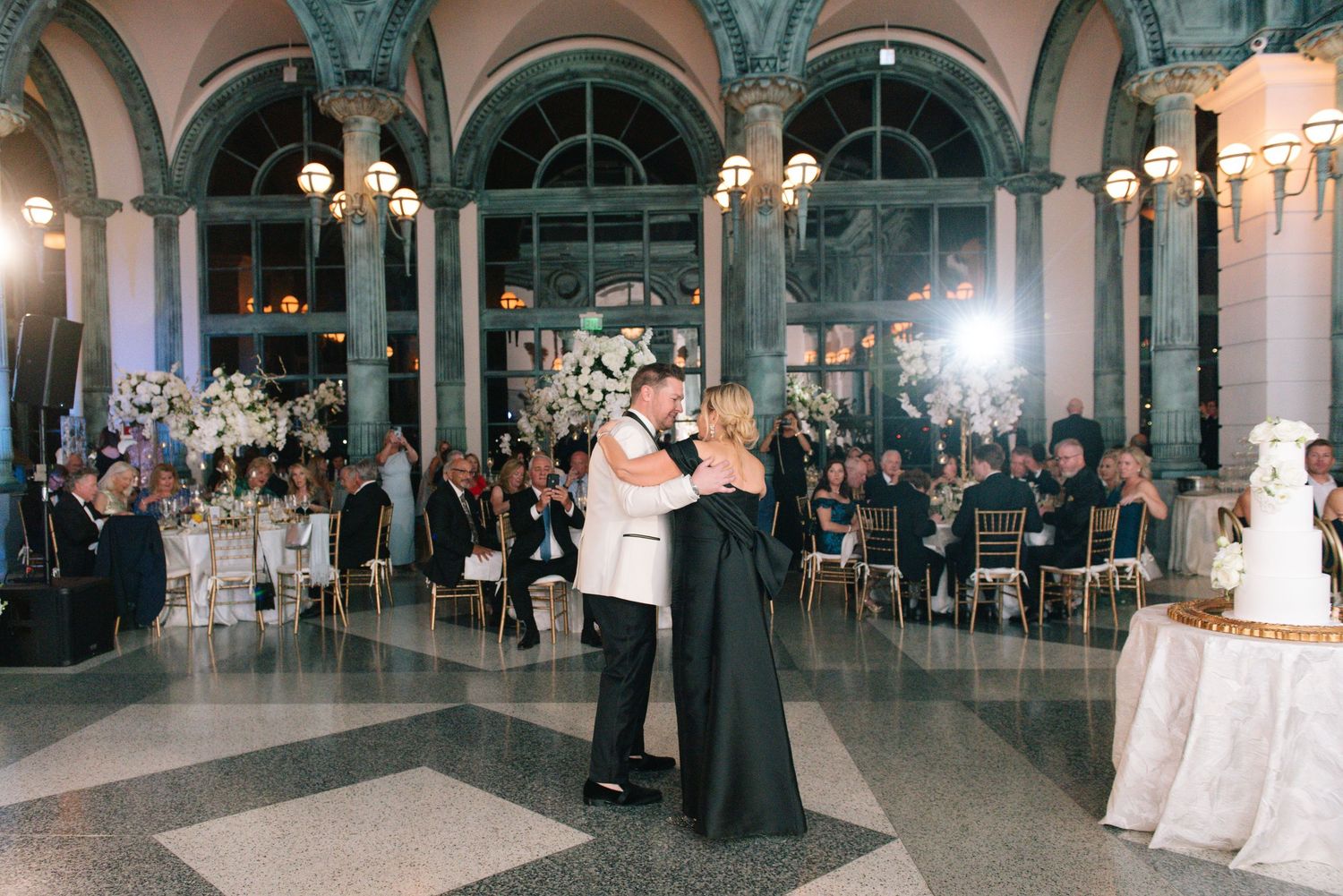 Couple sharing first dance in stunning ornate ballroom at black tie wedding reception.