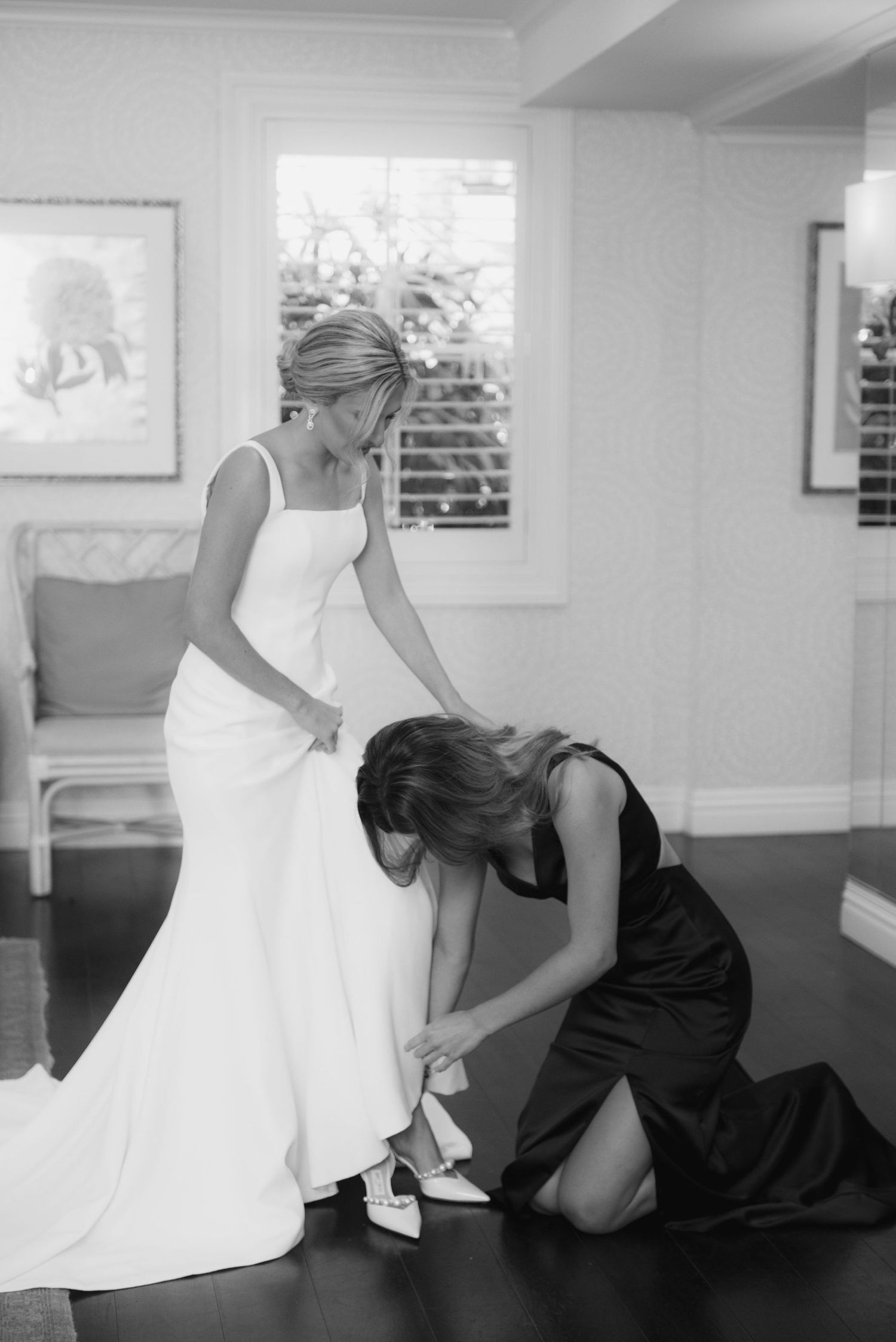 Wedding dress fitting and preparation moment captured in black and white.