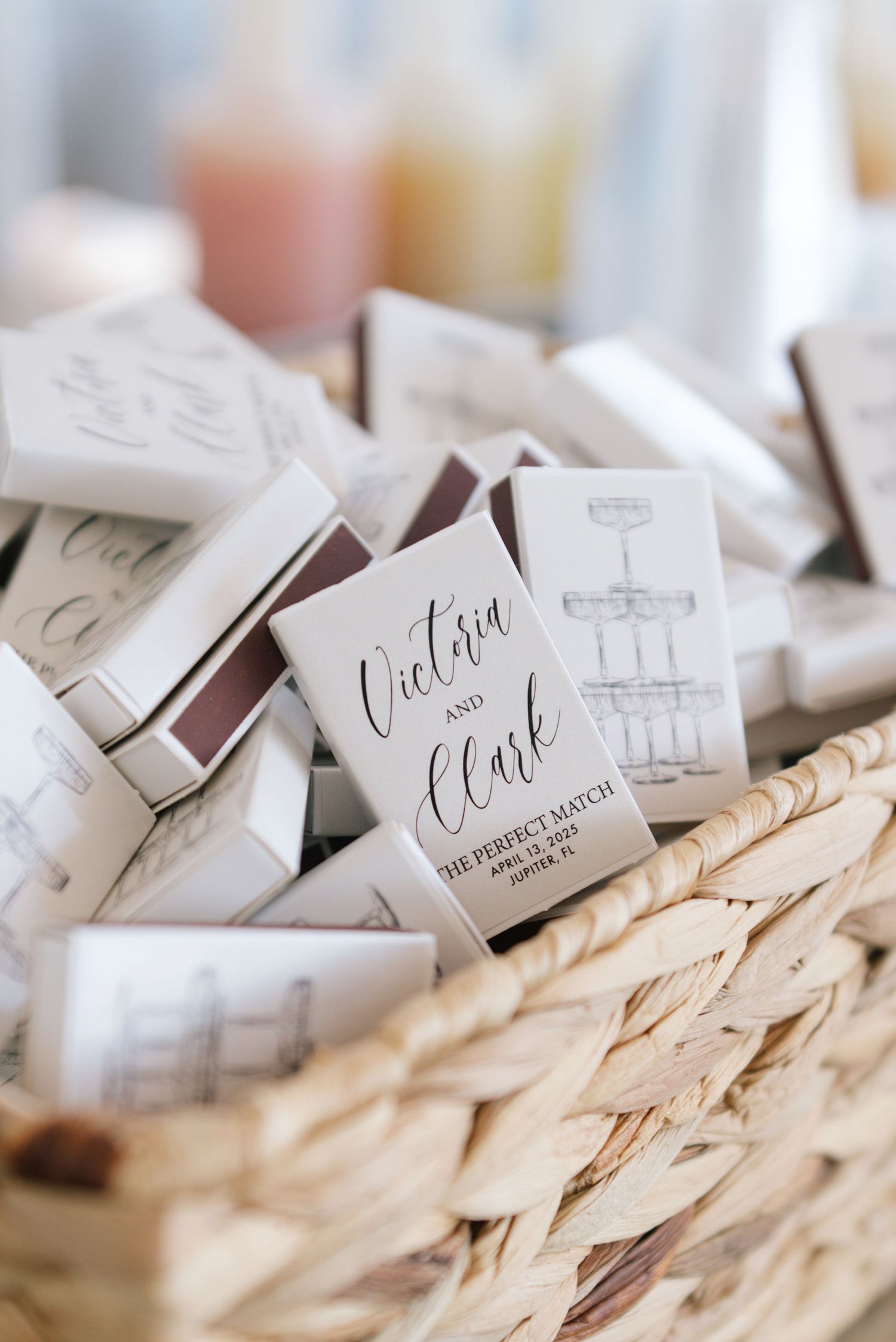Wedding matchbooks with custom calligraphy displayed in woven basket.
