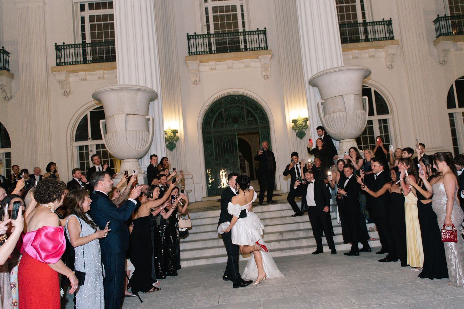 Grand entrance of a formal event with guests lining white columned hallway.
