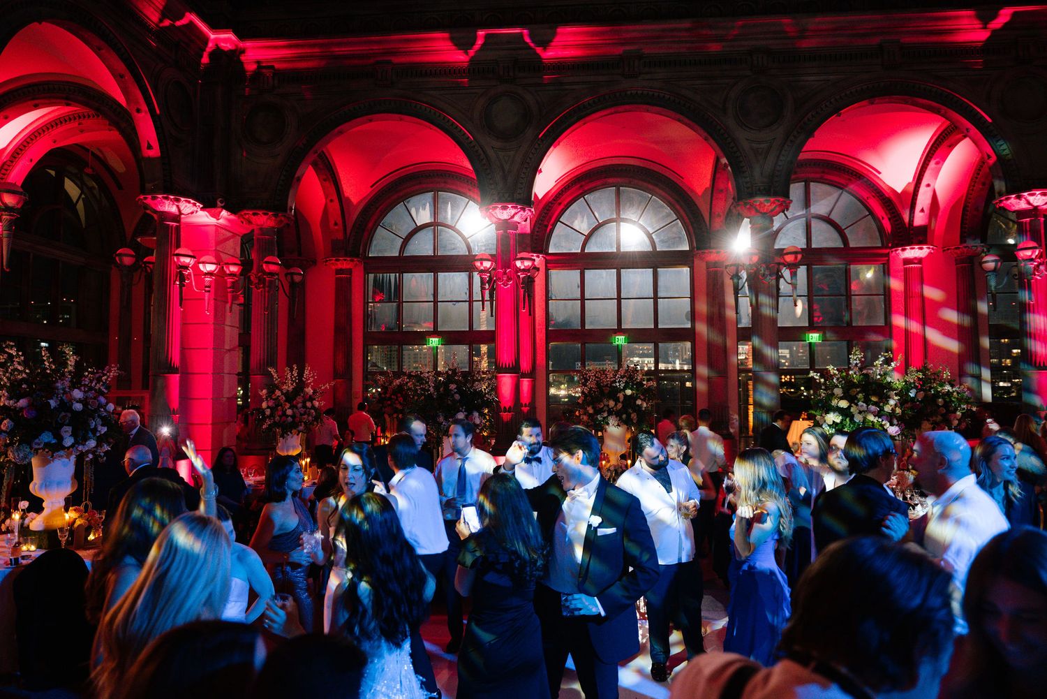 Wedding reception venue with dramatic red uplighting illuminating arched windows and architecture.