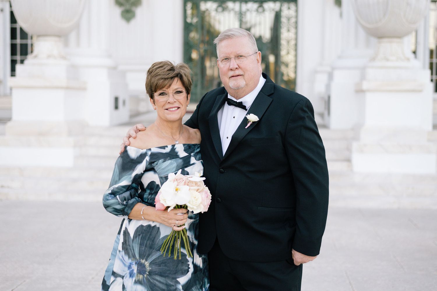 Wedding party members pose for formal portraits at an elegant white venue.