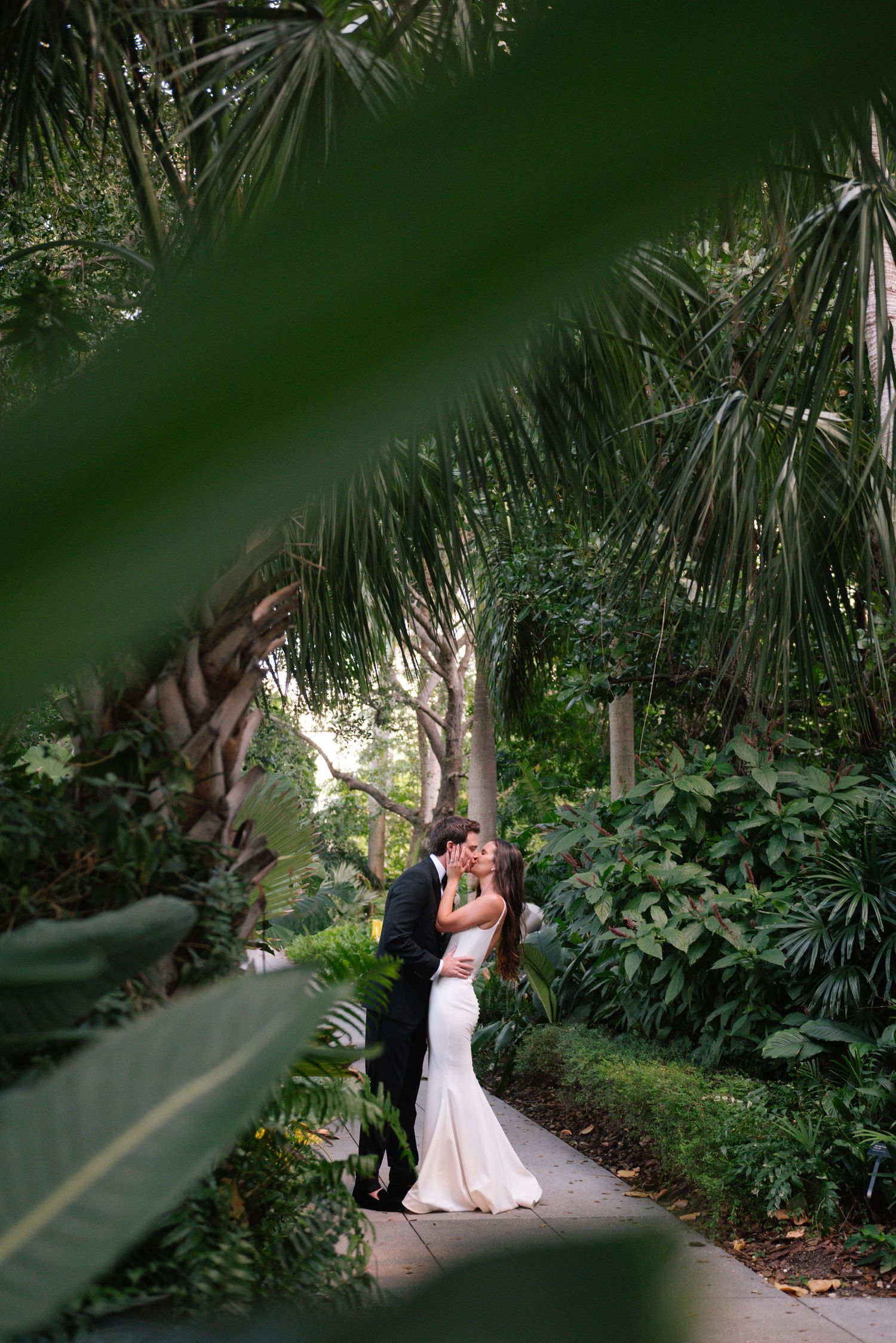 A romantic garden wedding scene with palm trees and tropical plants creating a natural green backdrop.