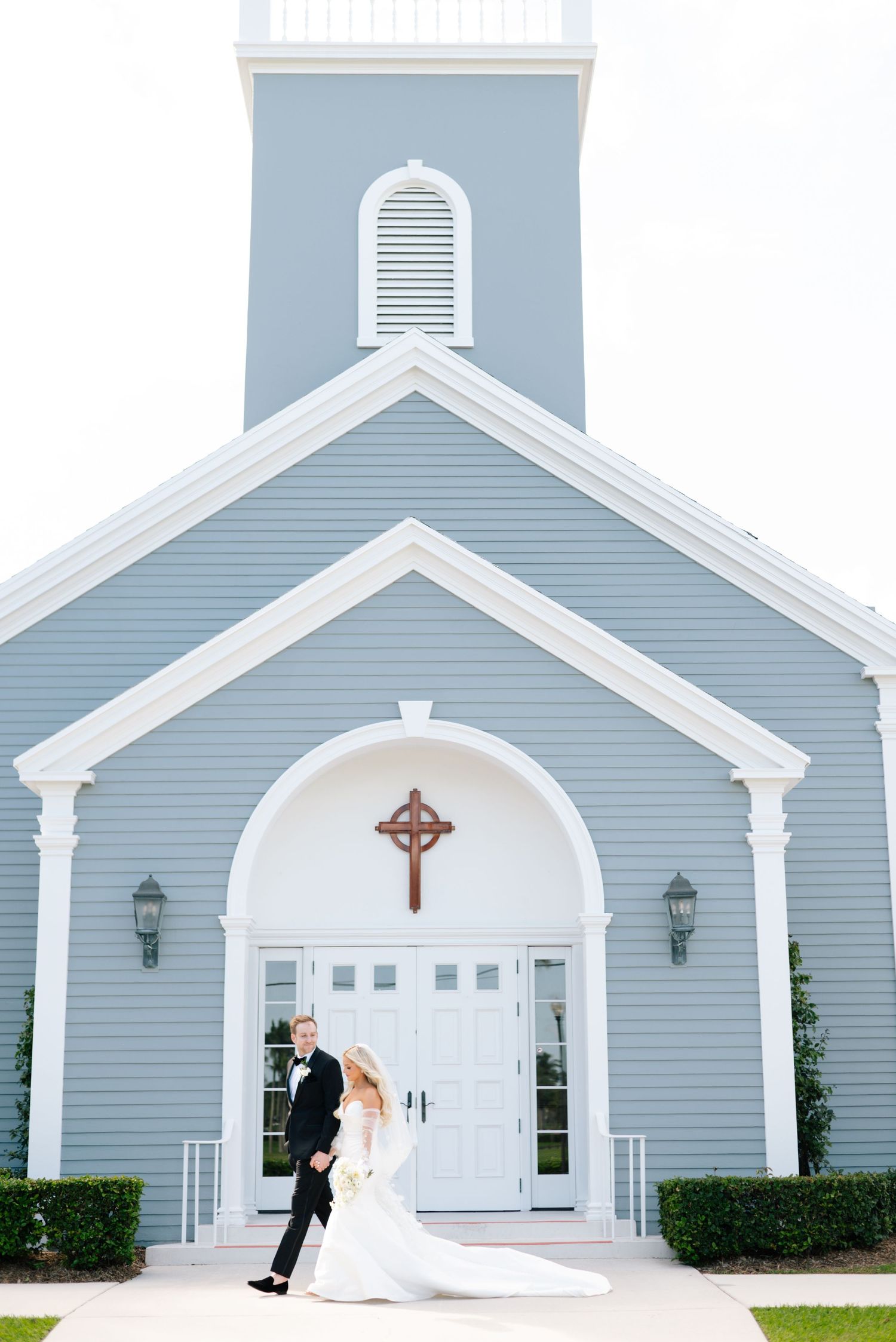 Wedding sequence outside a light blue and white church with classic architectural features.