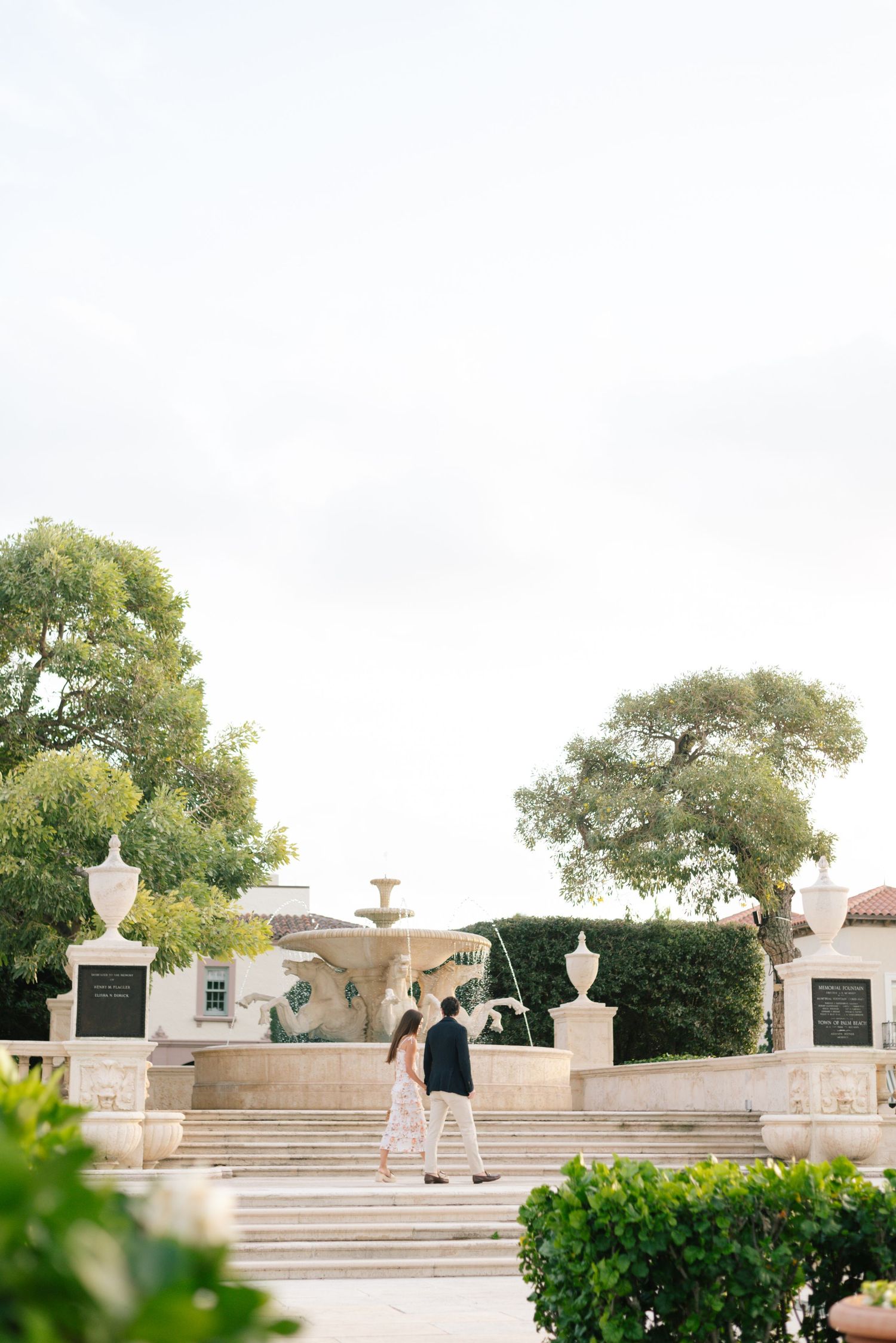 Elegant white stone staircase and balustrade surrounded by lush greenery in a formal garden setting.