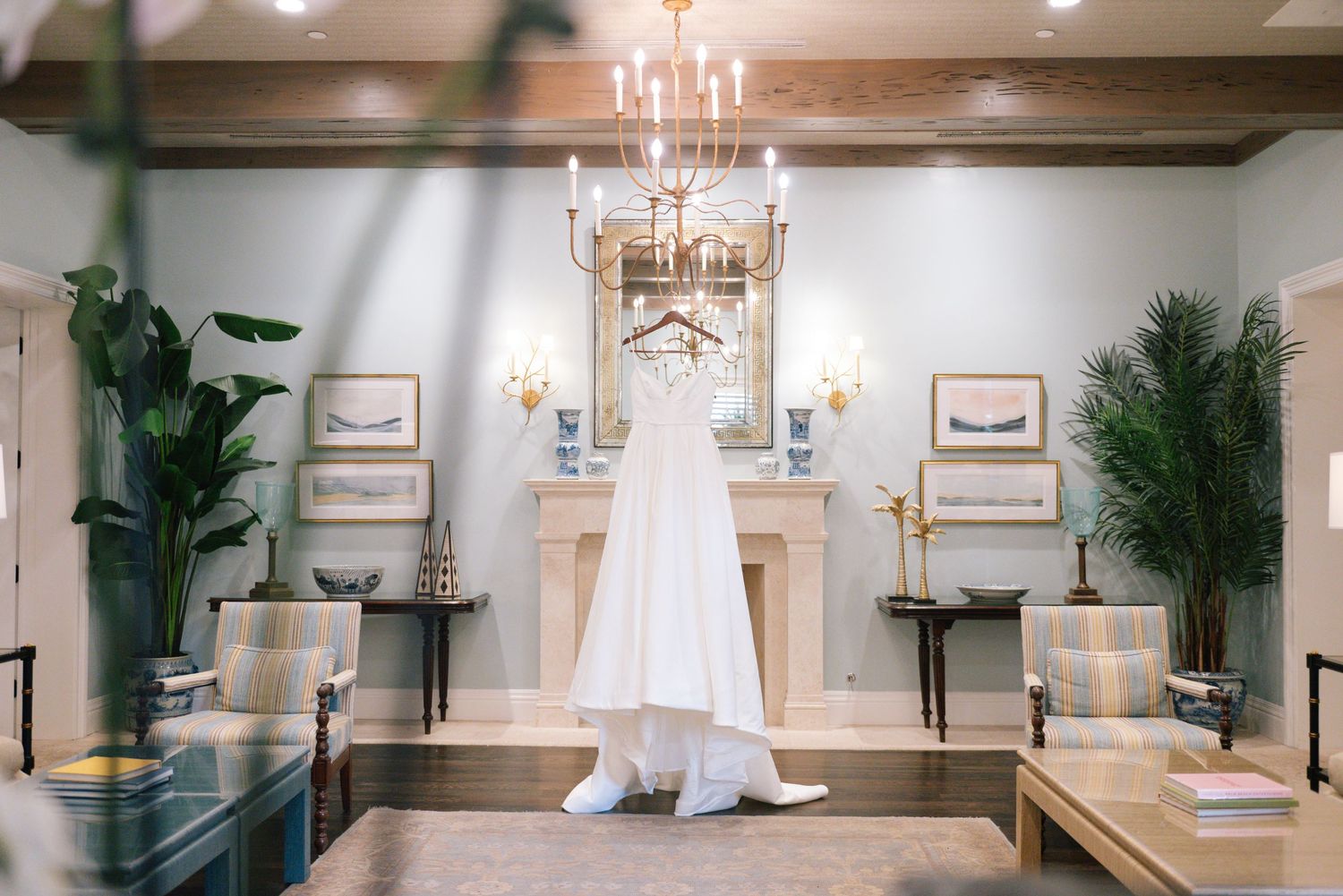 Elegant wedding venue interior with white walls, chandeliers, and palm plants creating a luxurious atmosphere.