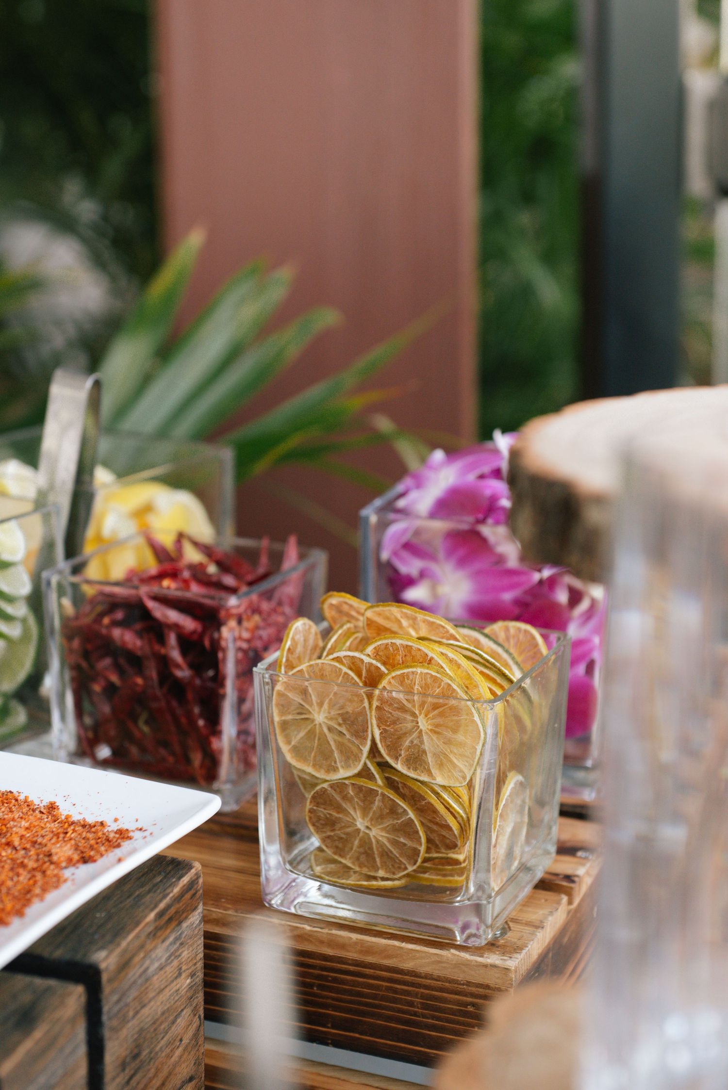 Decorative dried citrus slices and colorful garnishes displayed on wooden serving boards at an elegant event setup.