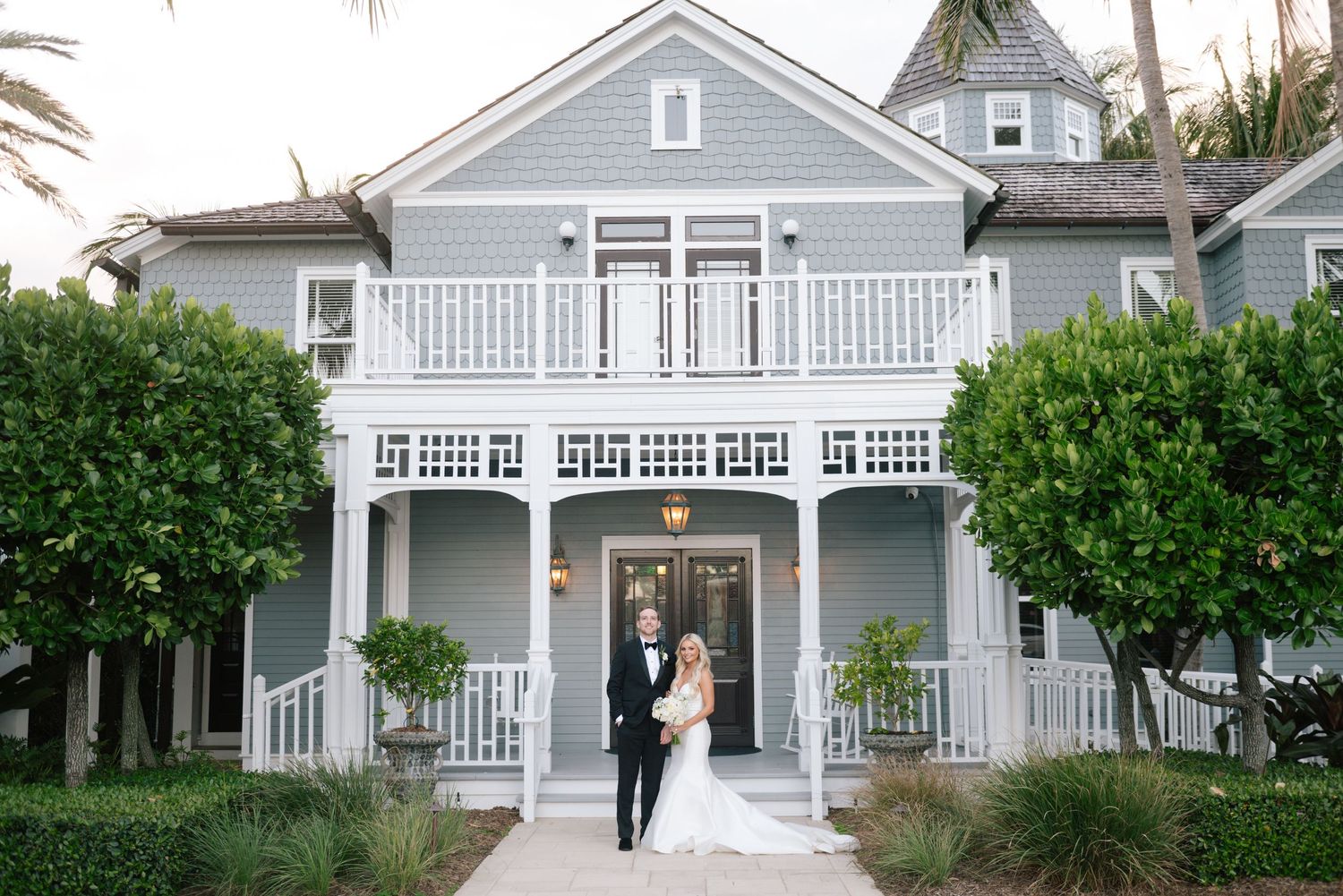 Classic white coastal house with wraparound porch and elegant architectural details.