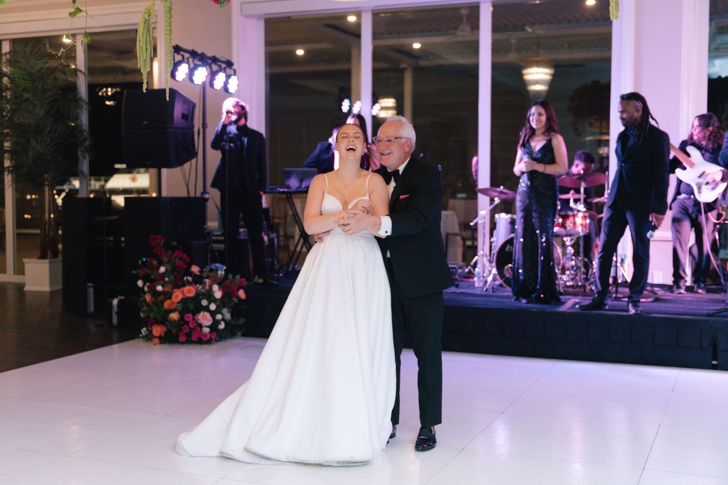Couples dancing together on an elegant white dance floor during a wedding reception.