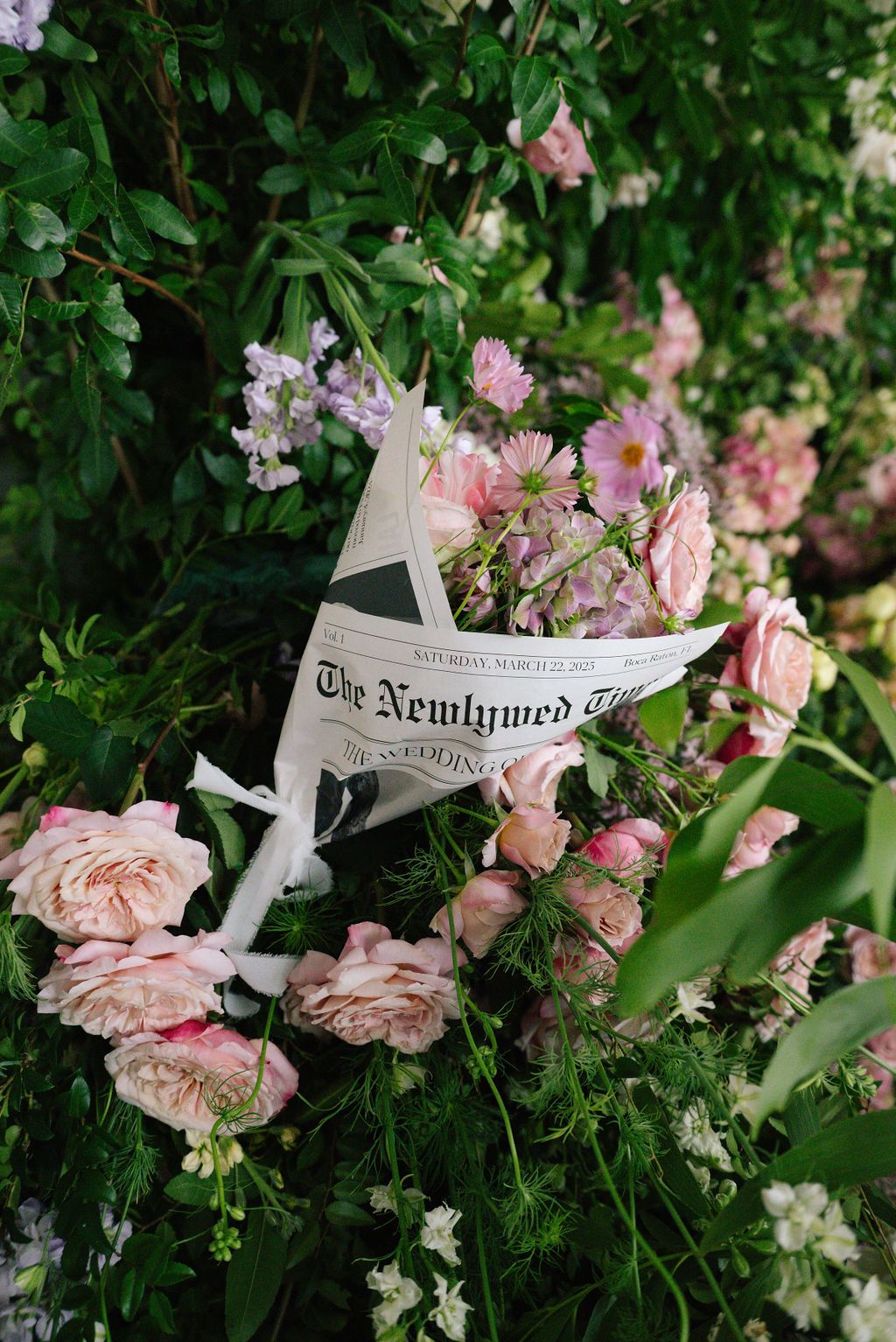 Newspaper pages artistically arranged among pink roses and garden flowers.