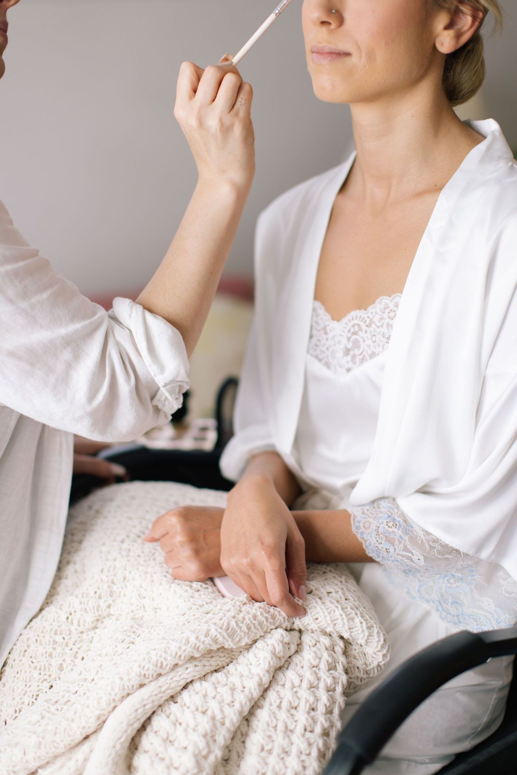 Person in white robe sitting with lace details visible.