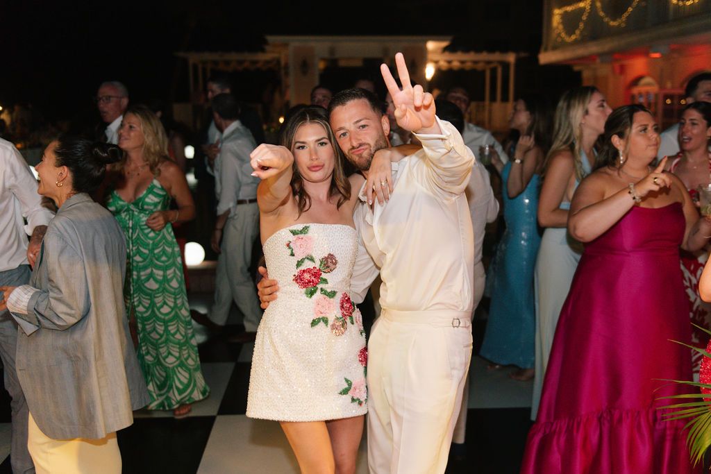 People dancing and celebrating at a lively wedding reception under warm lighting.