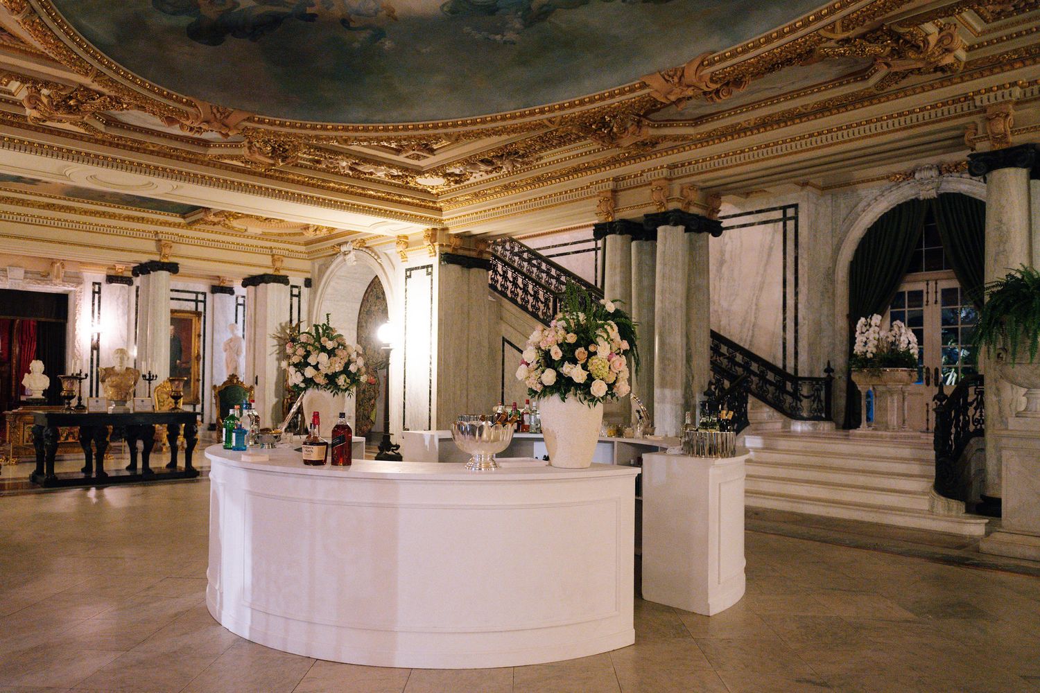 Panoramic view of an elegant wedding reception venue with white curved bars and ornate ceiling.