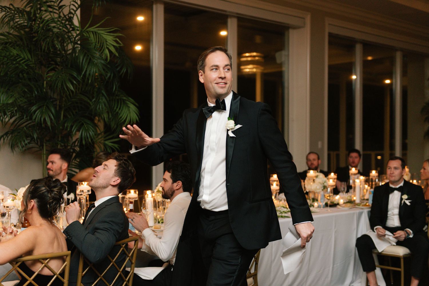 Wedding guests watch and cheer as the newlyweds perform their first dance in a decorated ballroom.
