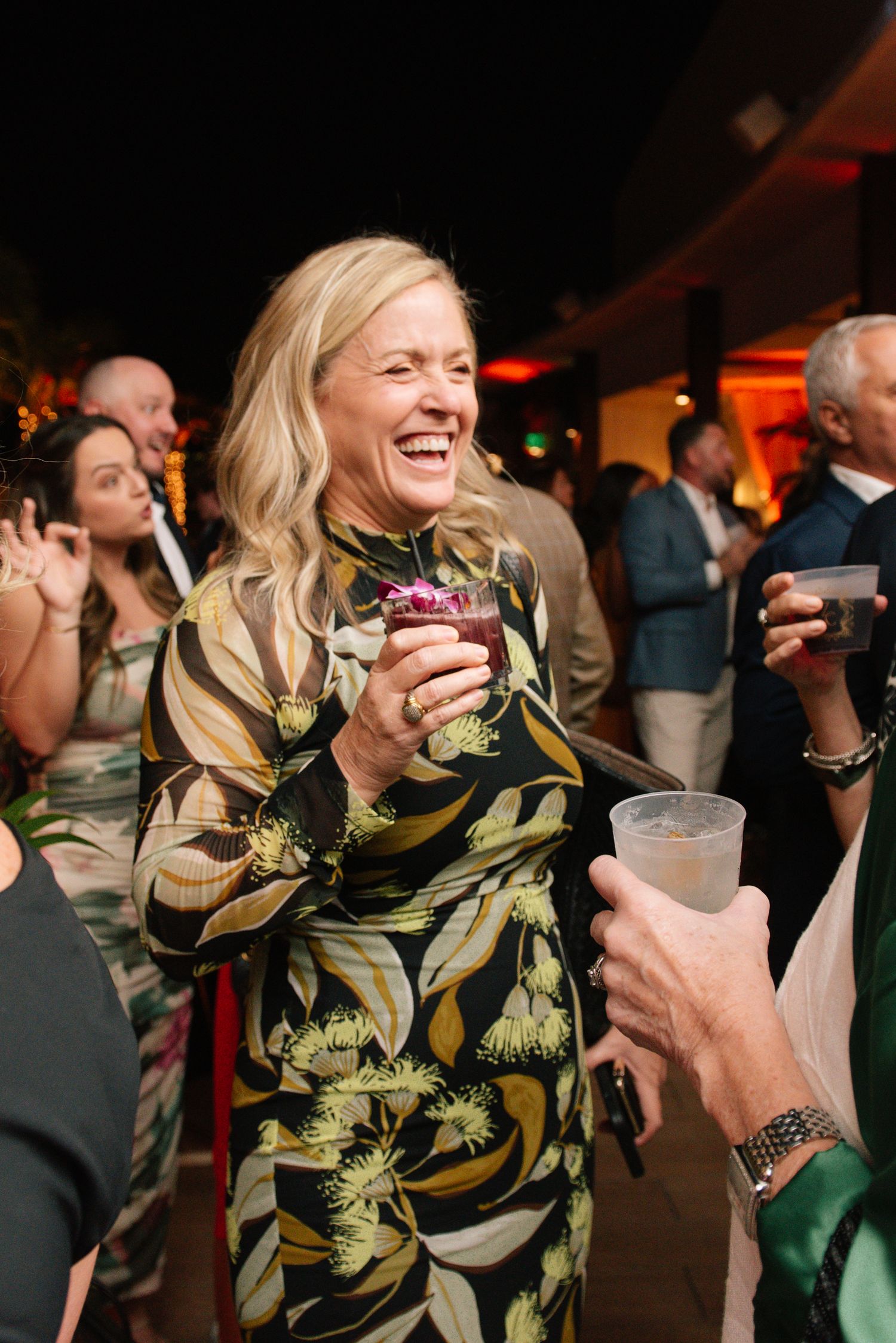 Party guests enjoying a lively celebration with tropical-themed decor and dramatic lighting.