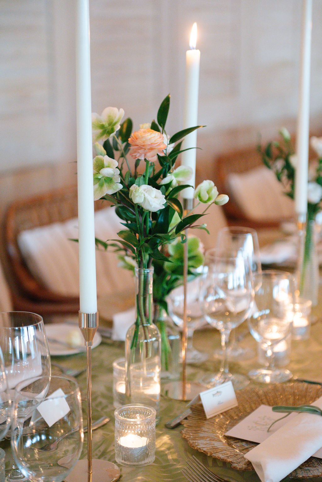 Elegant table decor with white taper candles, fresh flowers, and crystal glassware.