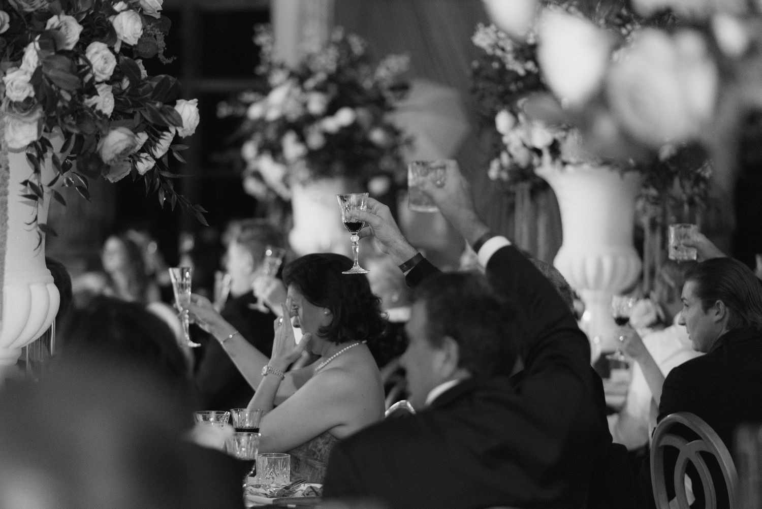 Black and white photo of wedding guests enjoying a formal reception dinner.