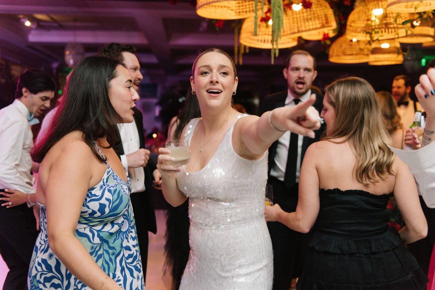 Guests dancing and celebrating at a wedding reception with purple ambient lighting.