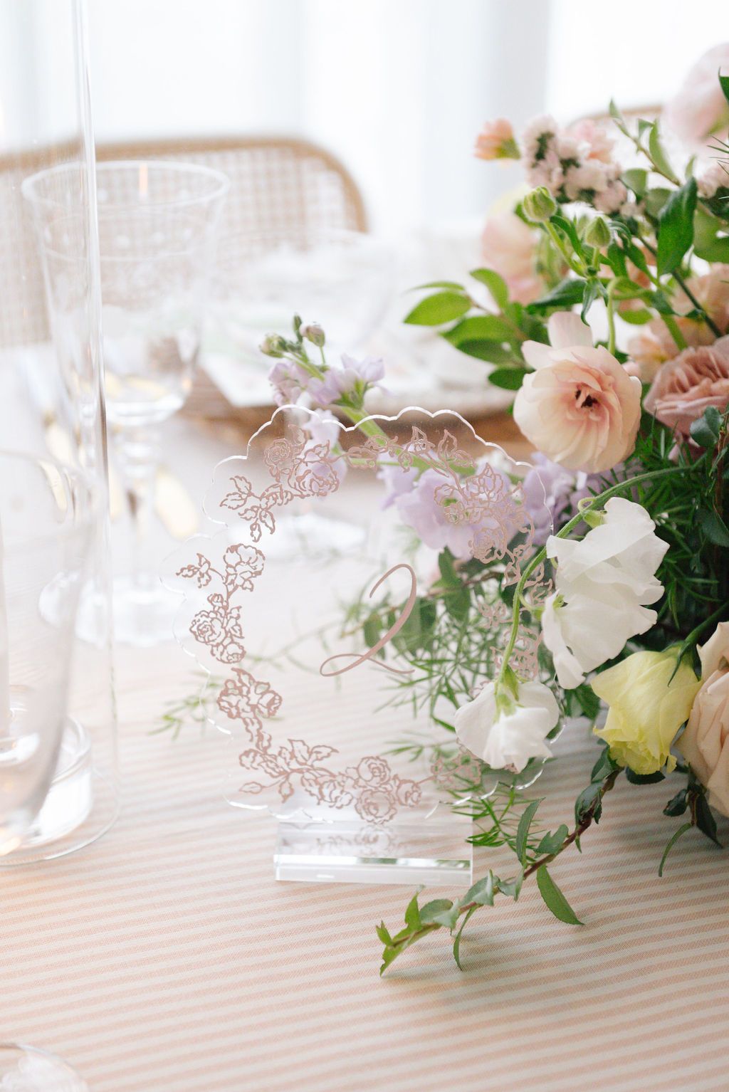 Elegant table setting with soft pink floral centerpieces and delicate glassware.