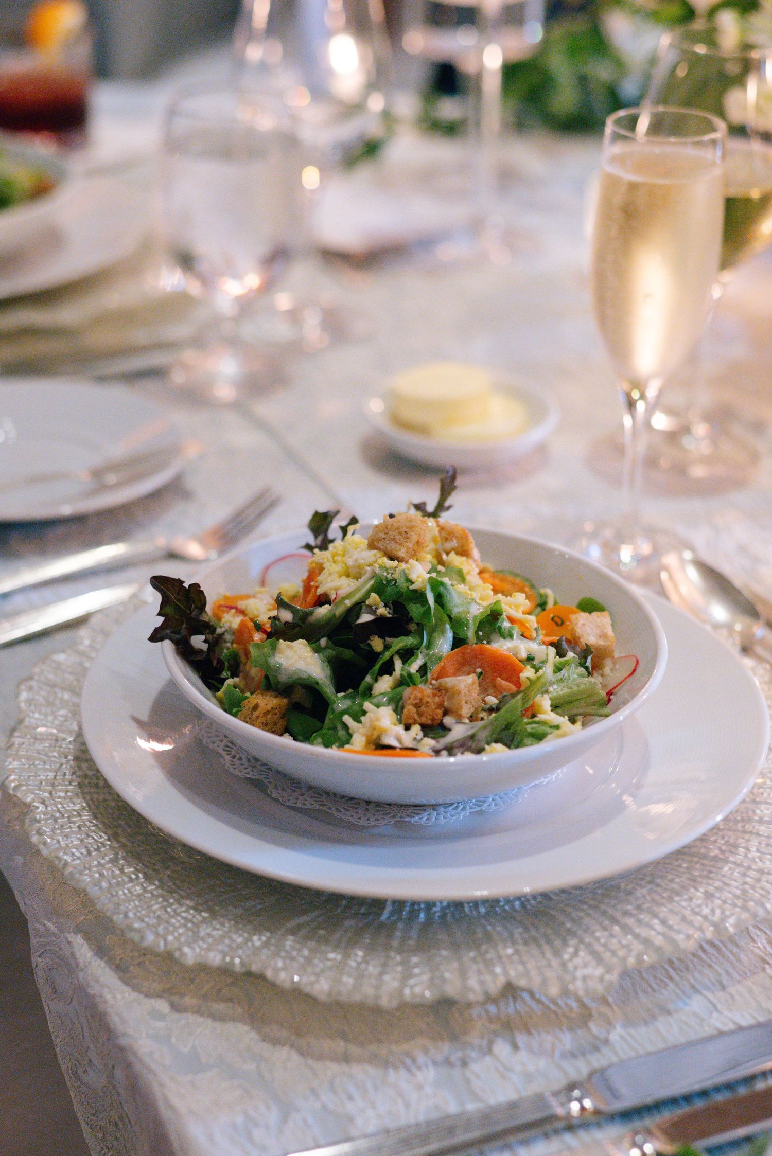 Fresh garden salad served on white china with champagne glass and elegant table settings.