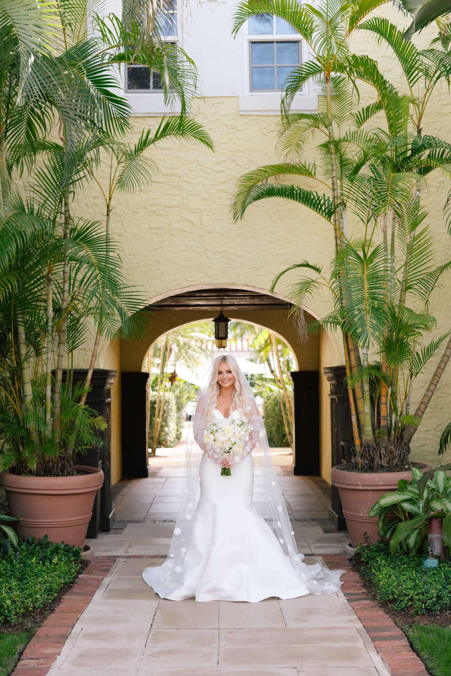 A bridal portrait session in a tropical courtyard with palm trees and arched walkways.
