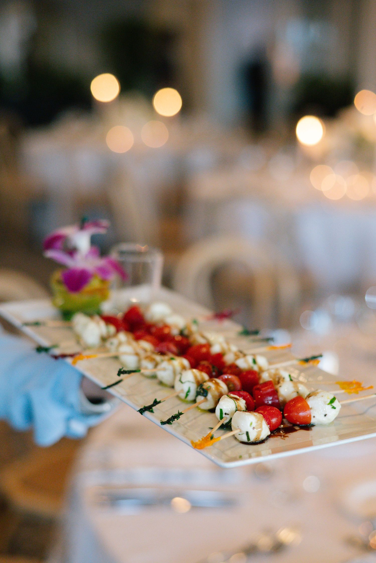 White serving platter with colorful appetizers arranged in a line against a softly blurred background.