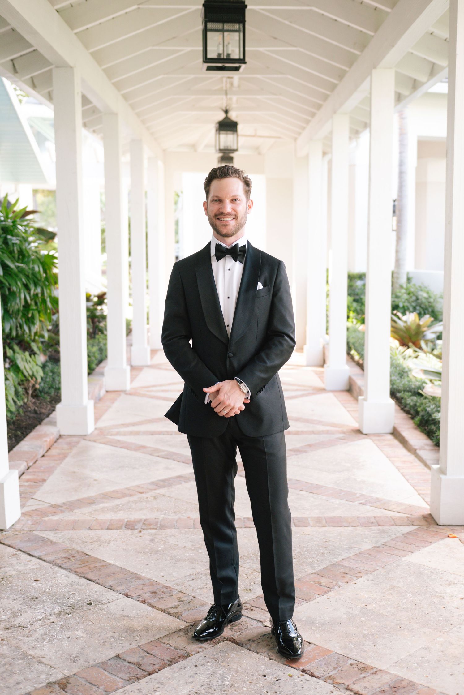 An elegant covered walkway with white columns and arches creates a beautiful wedding venue setting.