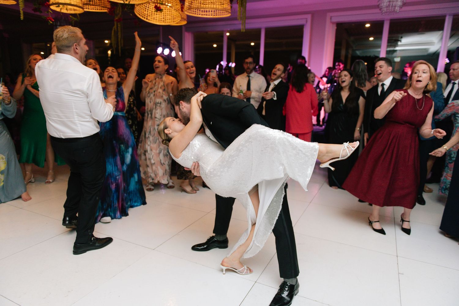 Wedding reception dance floor filled with guests celebrating under warm lighting.