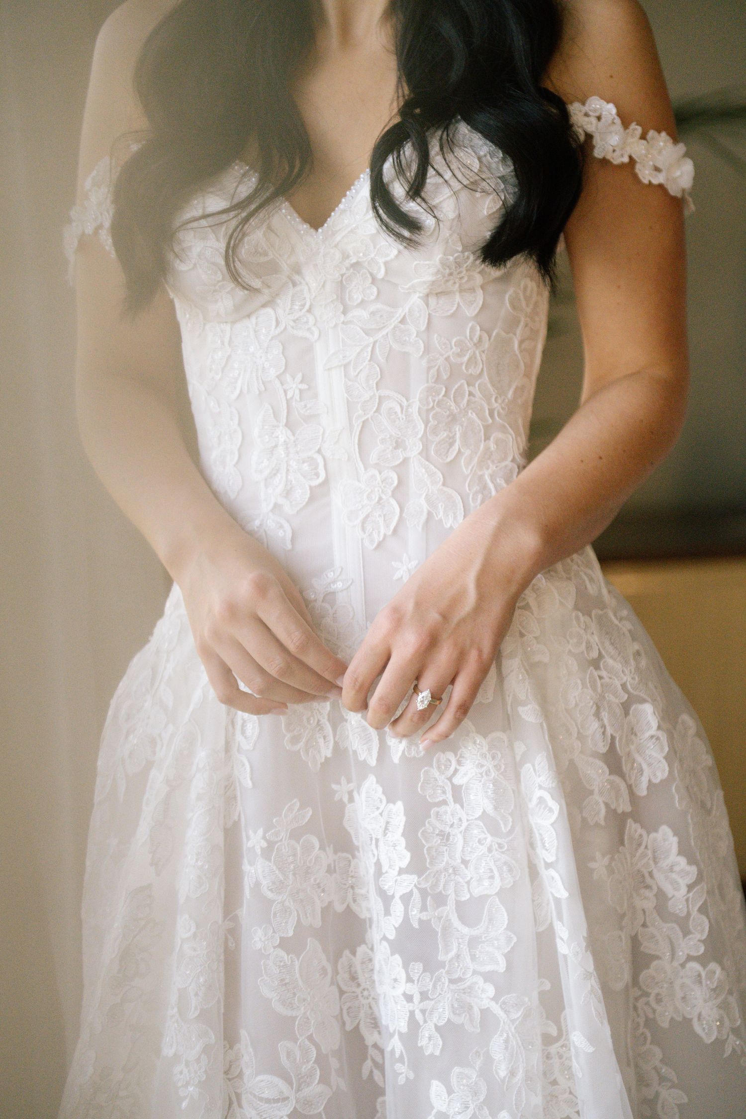 Close-up details of a white lace wedding dress with intricate floral patterns and embroidery.