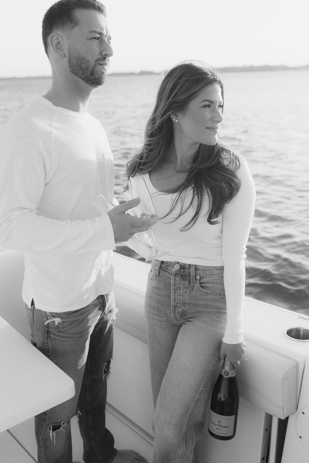 Romantic couple enjoying a boat ride at sunset wearing white tops and jeans.