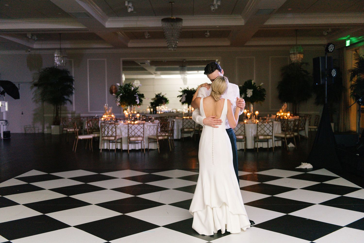 Romantic first dance captured on an elegant black and white checkered ballroom floor.