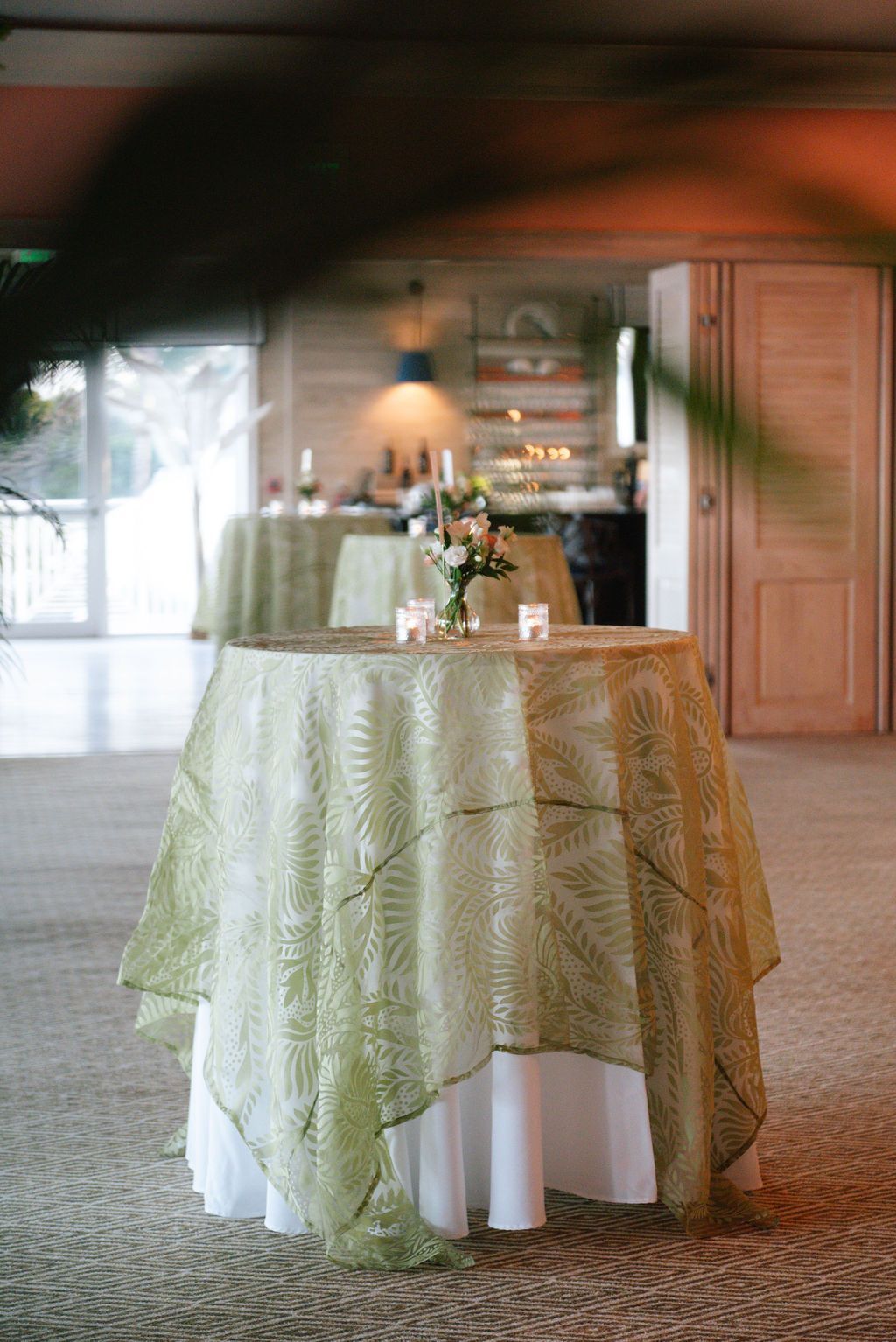 Close-up view of round tables with sage green overlays on white tablecloths.